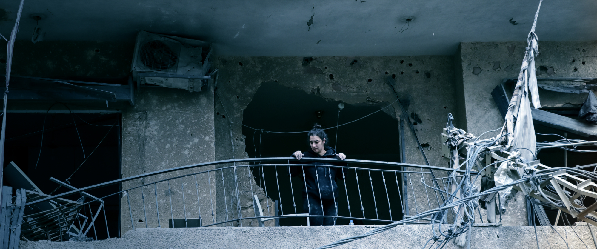 In the suburbs of Beirut, a woman assesses the damage to her ruined home.